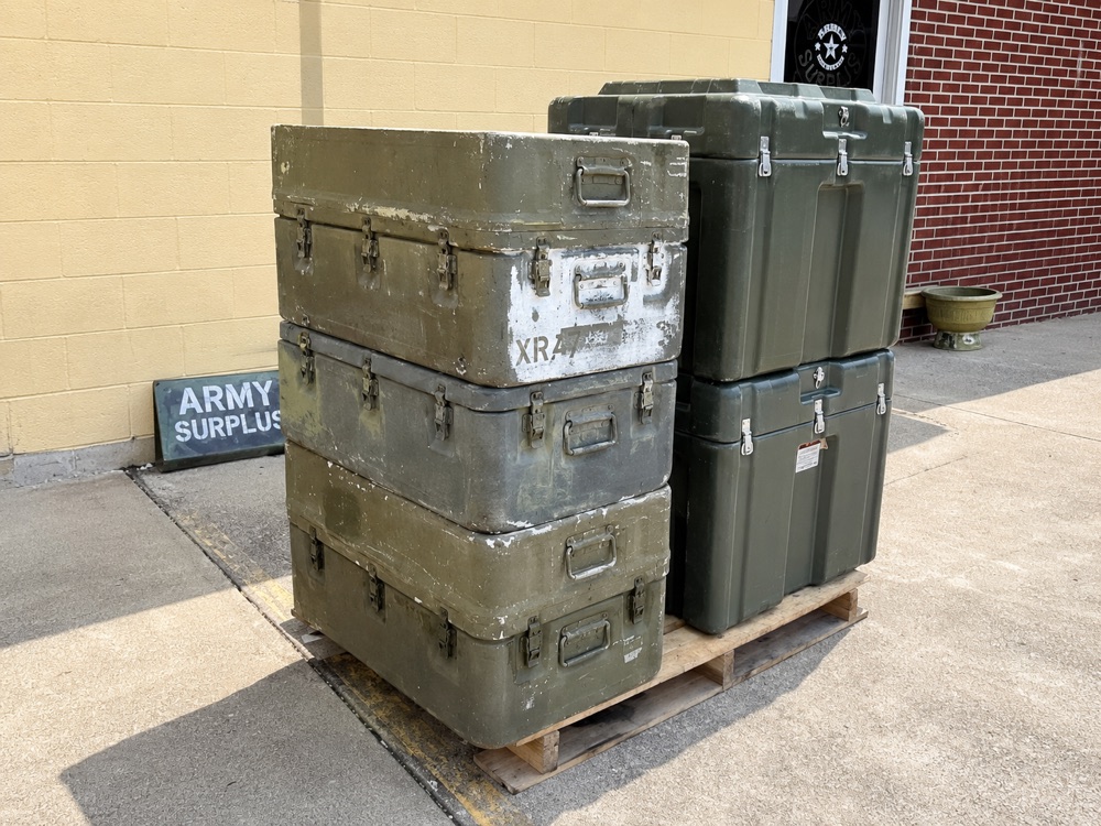 Pallet of OD green Hardigg military shipping cases outside Bossert's, heavy duty ribbed plastic cases stacked.