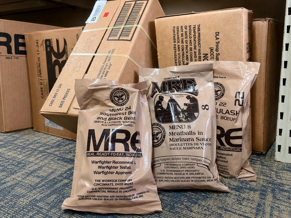 Stacks of MRE (Meals Ready to Eat) cardboard cases at Bossert's, government surplus rations packaging.